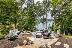 a patio with chairs and fire pit in the middle of it, surrounded by trees