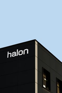 an airplane is flying in the sky above a black building that says halon on it