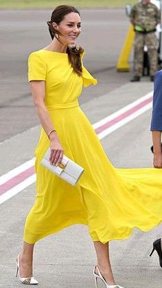 a woman in a yellow dress is walking down the street with her hand on her hip