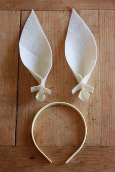 a pair of white hair ties on top of a wooden floor next to a headband