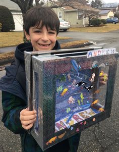 a young boy holding up a box with an image on it