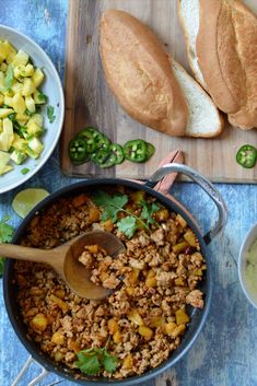 the meal is ready to be eaten on the wooden cutting board with bread and vegetables