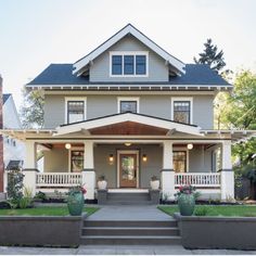 a gray house with two front porches and steps leading up to it