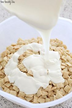 a bowl filled with cereal and cream being poured into it to make a cheesy snack