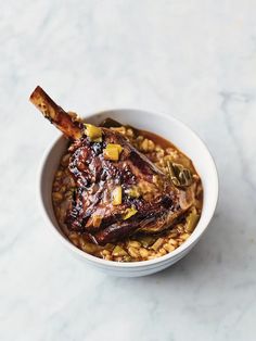 a white bowl filled with food on top of a marble counter next to a spoon