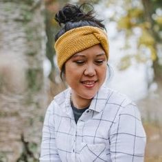 a woman wearing a yellow headband and looking down at her cell phone in the woods