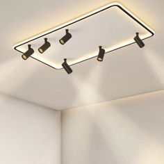 three lights that are on the ceiling above a bed in a room with white walls