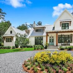 a white house sitting on top of a lush green field next to a gravel road