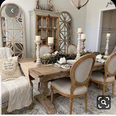 a dining room table and chairs with candles on them in front of a china cabinet