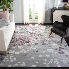 a living room area with a couch, chair and rug on the floor in front of a window