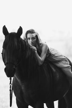 a woman riding on the back of a black horse