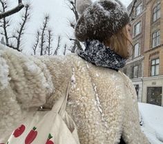 a person walking in the snow with a large stuffed animal on their back and an apple print tote bag