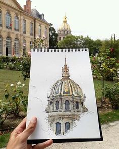 a hand holding up a drawing of a building