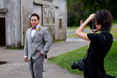 a man and woman are taking pictures in front of a barn