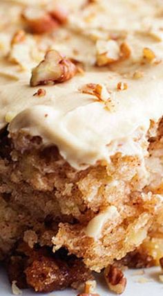 a close up of a piece of cake with frosting and nuts on the top