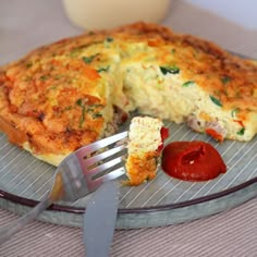 an omelet on a plate with a fork next to it and ketchup