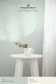 a white table with a cup and flowers on it