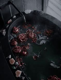 red flowers are floating in a large metal bowl filled with water and ice cubes