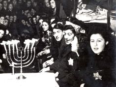 a group of people sitting around a table with a menorah on it