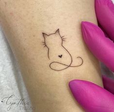 a small cat tattoo on the left side of the leg, with a black outline