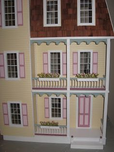 a doll house with pink shutters and balconies on the second floor is shown