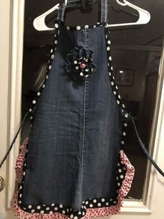 an apron hanging on a door with polka dot trimmings and flower decoration in the center