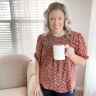 a woman is holding a coffee cup in her hand and standing next to a couch