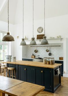 a kitchen with an island, table and stools next to it in front of a clock on the wall