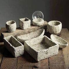 an assortment of stone bowls and cups on a wooden table with a glass ball in the middle