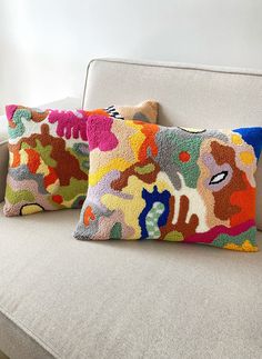 two colorful pillows sitting on top of a couch