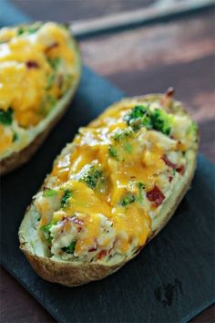 two pieces of bread with broccoli and cheese on them sitting on a black plate