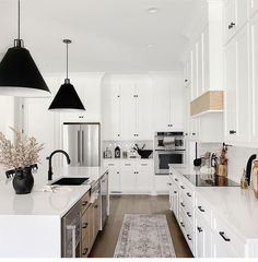 a kitchen with white cabinets and black pendant lights