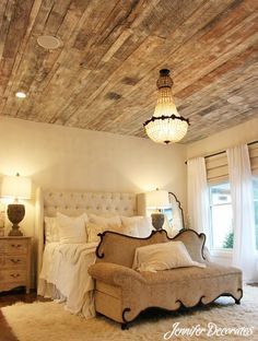 a bed room with a neatly made bed and a chandelier hanging from the ceiling