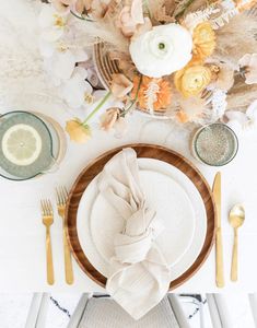 the table is set with plates, silverware and flowers