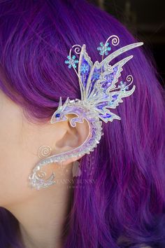 An ice dragon ear cuff crafted in silver-plated wire and angelina film that sparkles magically in the sunlight. The film is very iridescent, so the color may vary depending on viewing angle and lightning. The ear cuff is very easy to wear. It is designed to hook over the back of your ear like a Blue Tooth device and can be gently shaped to perfectly fit your ear. No piercing is needed. This magic ear cuff looks gorgeous either with short or long hair. You may do your hair or let it down, so that Dragon Ear Cuffs, Glass Bead Crafts, Elf Ear Cuff, Fairy Ears, Costume Ball, Dragon Earrings, Elf Ears, Mermaid Earrings, Wrap Earrings