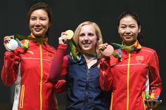 three women standing next to each other holding up medals