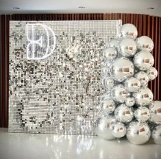 silver balls are stacked on top of each other in front of a wall with a monogram design