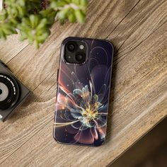 an iphone case sitting on top of a wooden table next to a camera and plant