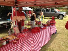 a man and woman standing under a tent at a picnic table with food on it