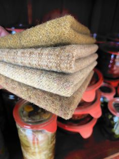 a stack of towels sitting on top of each other in front of some jars filled with food