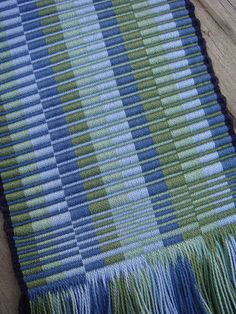 a blue and green striped rug with fringes