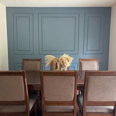 a dining room table with chairs and a vase on it