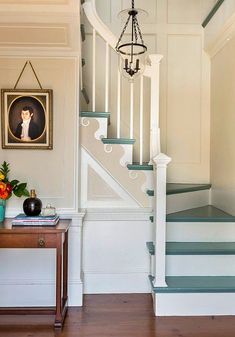 there is a painting on the wall next to some stairs and a table with flowers