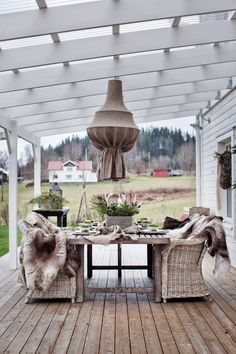 an outdoor dining area with wicker chairs and table on wooden deck overlooking grassy field