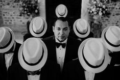 a man in a suit and bow tie surrounded by men with hats on their heads