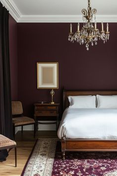 a bedroom with a bed, chandelier and purple walls