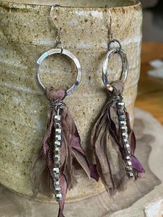 a pair of earrings with tassels hanging from them on top of a vase