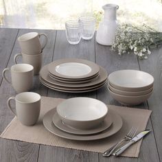 a table set with plates, cups and utensils on top of a placemat