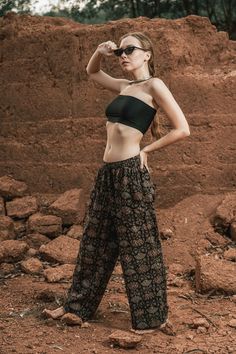 a woman standing on top of a dirt field wearing sunglasses and a black crop top