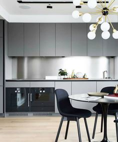 a modern kitchen and dining area with grey cabinets, white counter tops and black chairs